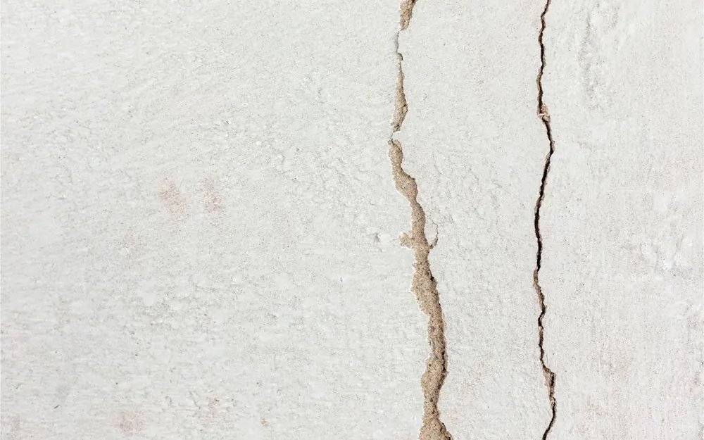Close-up of cracks running through a white painted wall
