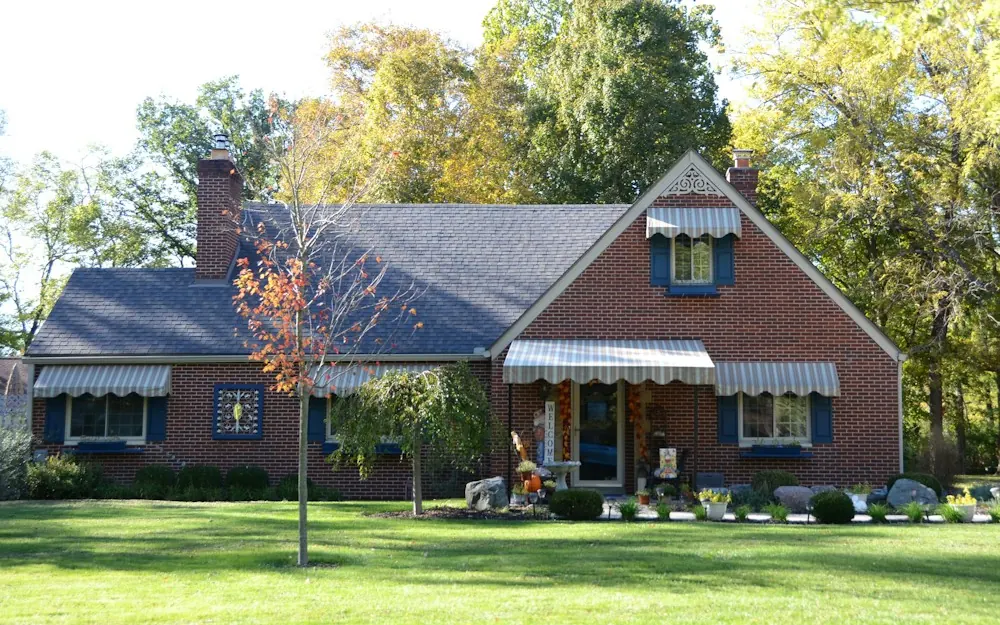 Red brick single-family home with a green lawn and shade trees